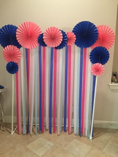 some paper fans are lined up against the wall with pink, blue and white ribbons