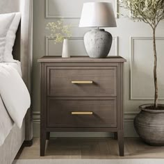 a nightstand with two drawers and a lamp next to it