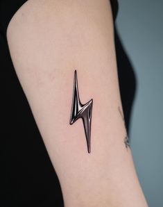 a small black lightning bolt tattoo on the arm