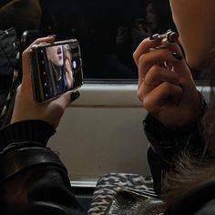 a woman taking a selfie with her cell phone on the train while sitting down