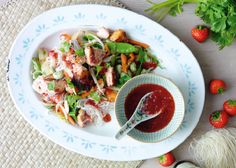 a white plate topped with salad next to a bowl of ketchup