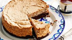 a cake on a plate with one slice cut out and the other half eaten, next to a cup of tea