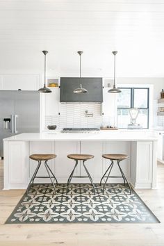 a kitchen with an island and stools in the center, along with white cabinets