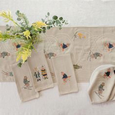 the table is set with napkins and placemats, which have embroidered images of people on them