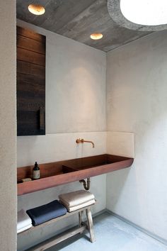 a bathroom with a sink and stool in the corner, along with two lights above it