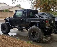 a black jeep parked on the side of a road next to a car in front of a house