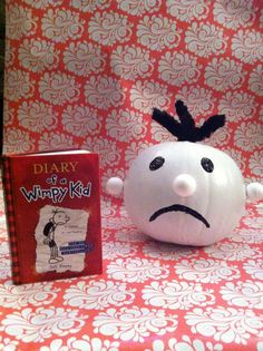 a white pumpkin sitting next to a book on top of a red and white table cloth