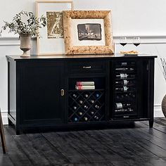 there is a black cabinet with wine bottles on it and two framed pictures next to it