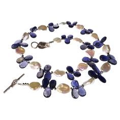 Own the jewelry you wish for Custom made Blue Iolite Briolettes in threes accented with glowing white Keshi Pearls necklace. This unique necklace creates a sensation, the iolites are big and bright. Iolite is a trichroic gemstone. It will look blue, silver, or yellow depending on the direction, how nifty is that! The pearls are glowing and separated from the blue Iolites with sparkling silver accents. This 21 inch necklace is secured with a Turkish Sterling Silver toggle with a leaf motif. One o