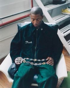 a man sitting in a chair with a chain around his waist and wearing green pants