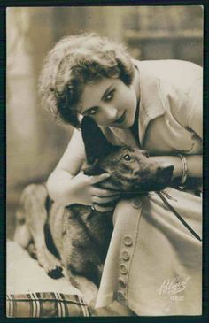 an old black and white photo of a woman holding a dog in her lap,