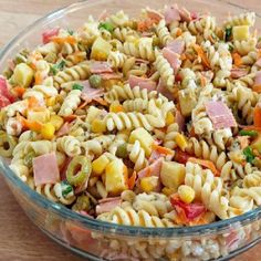 a bowl filled with pasta salad on top of a wooden table