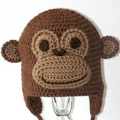 a crocheted monkey hat is hanging on a hook with its eyes closed and ears wide open