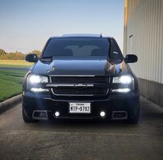 a black truck parked in front of a building with two lights on it's sides