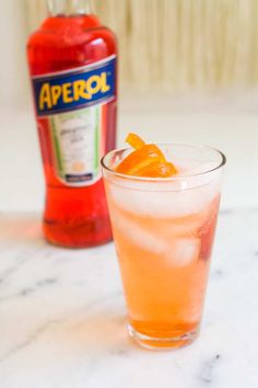 an orange drink sitting on top of a table next to a bottle