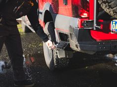 a man is changing the tire on his red truck