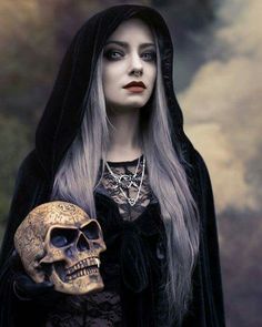 a woman dressed as a skeleton holding a skull in her right hand and wearing a black cloak