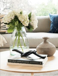 a vase with white flowers sitting on top of a table in front of a couch