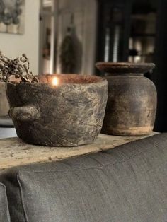 an old wooden bowl with a candle in it on a table next to two vases