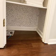 an open closet with towels on the floor and toilet paper stacked in front of it