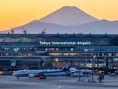 an airport with two planes parked at the gates and mountains in the backgroud