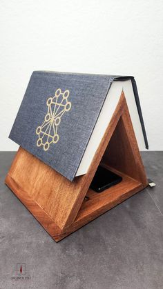 an open book sitting on top of a wooden stand with a cover over it's face