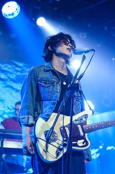 a man standing in front of a microphone and guitar