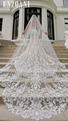 a woman in a wedding dress with a veil on her head is walking down some steps