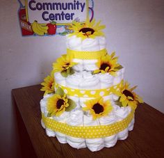 a diaper cake with sunflowers and polka dots on the bottom, sitting on top of a table