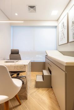 an office with white walls and wooden flooring is pictured in this image, there are two chairs at the desk