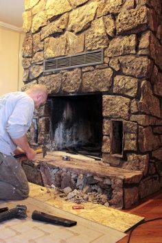 a man working on a stone fireplace in his living room