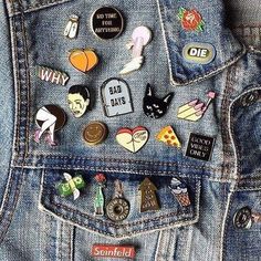 the back pocket of someone's jean jacket with many pins on it, all in different shapes and sizes