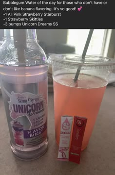 a cup of water next to a bottle of unicorn's dream drink on a table