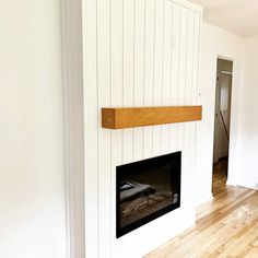 Fireplace surround in Lincoln, NE, featuring vertical shiplap painted white, black electric fireplace, and custom wood mantle in honey-colored stain. Vertical Shiplap Mantle, Shiplap On Sides Of Fireplace, Shiplap Vertical Fireplace, White Wood Panel Fireplace Wall, Vertical Panel Fireplace, Vertical Paneling Fireplace, Vertical Boards On Fireplace