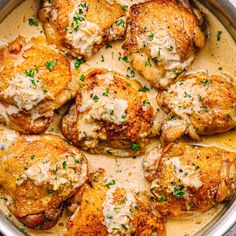 some chicken is cooking in a skillet on the stove with broth and parsley