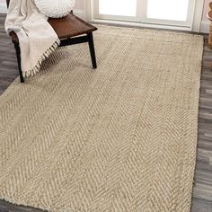 a large rug in the corner of a room with a chair and window behind it