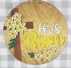 a wooden sign that says he is risen with flowers and a cross on the front