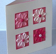 a card with pink and white paper flowers on the front, attached to a box