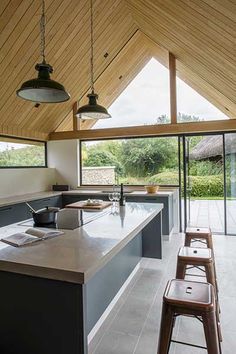 an open kitchen and dining area with large windows on the ceiling, along with wooden stools