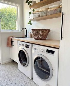 a washer and dryer in a small room with open shelving on the wall