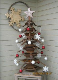 a christmas tree made out of old tires and other items is hanging on the side of a house