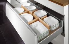 an open drawer with plates and bowls in it