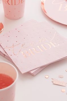 pink napkins with gold foil lettering on them next to two cups and spoons