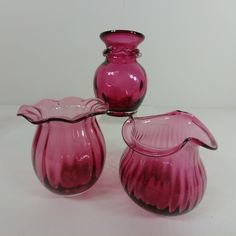 three pink glass vases sitting next to each other