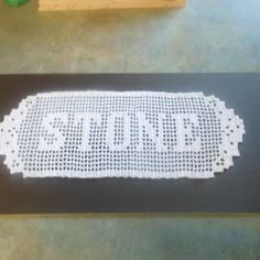 a piece of white crocheted paper with the word stop written on it, sitting on a table