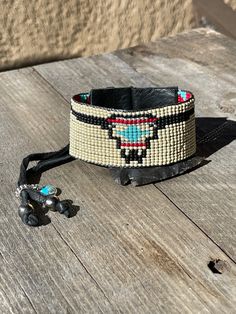 All your favorite Southwestern rich colors packed into one cuff. Stack it with some of your favorite pieces or wear alone as a show piece. Made with: * Toho - glass seed beads * Black Leather * Silver button (plated) * Sterling silver/Turquoise charm * Buffalo nickel charm * 2 Navajo pearls * Sterling silver charm holder * Black deer skin lace Note: Our new leather cuffs have been made so that one size fits all. It works like a bit like the draw string/leather method. The excess deer skin lace w Black Deer, Long Horn, Steer Skull, Turquoise Charm, Navajo Pearls, Charm Holder, Buffalo Nickel, Leather Cuff Bracelet, Bead Loom Bracelets