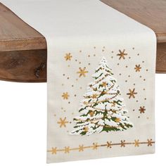 a white table runner with a christmas tree and snowflakes on the top, hanging from a wooden shelf