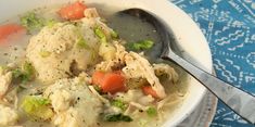 a bowl of chicken and dumpling soup on a blue tablecloth with a spoon