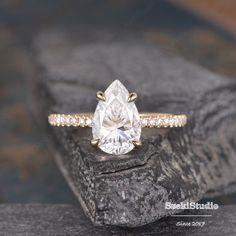 a close up of a ring on a rock with a diamond in the center and side stones around it