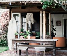 a wooden table sitting next to a white surfboard on top of a brick floor